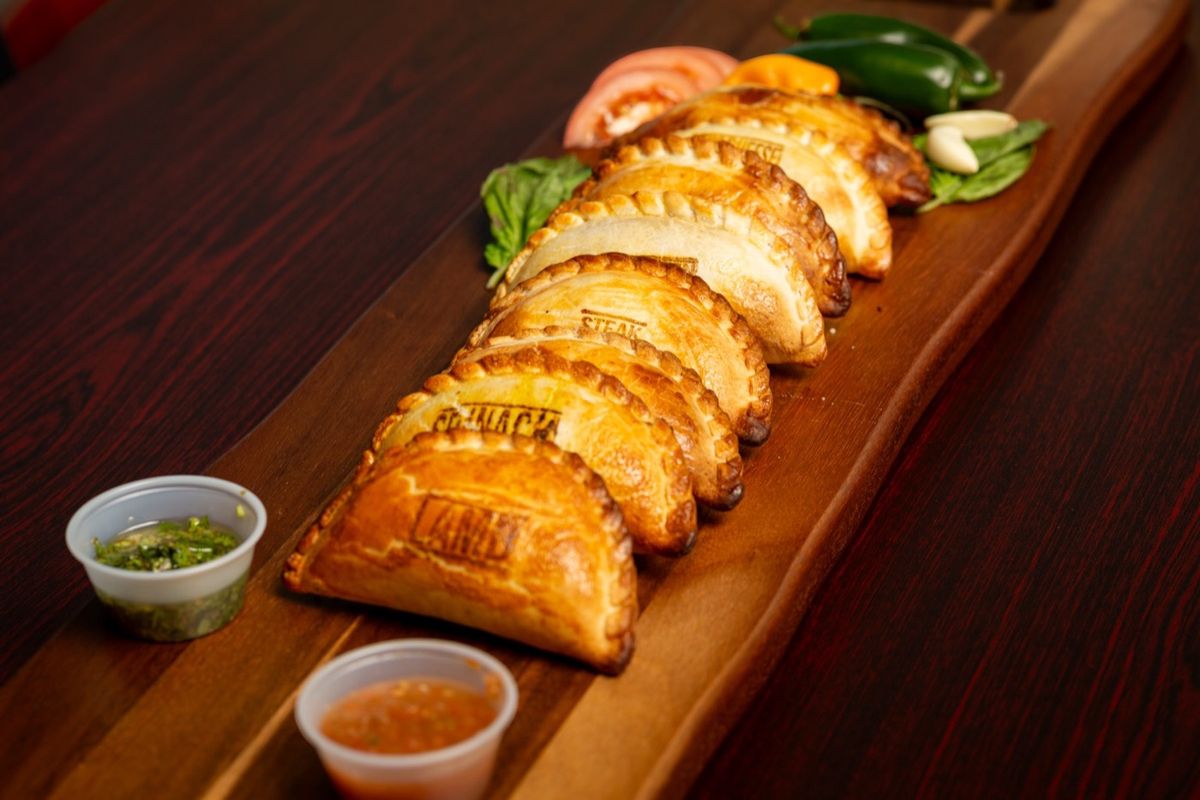 A long board of empanadas with dipping sauces